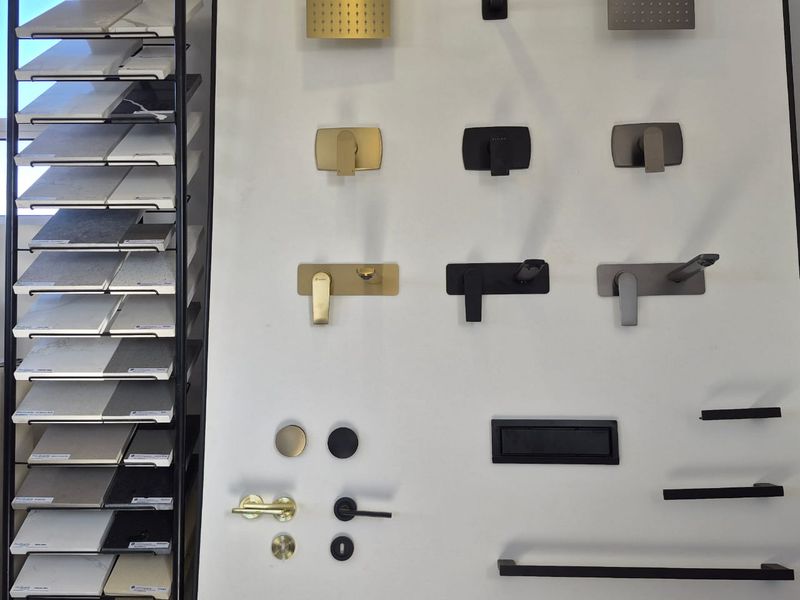 A display board showcasing various bathroom fixtures, including shower heads, faucet mixers, door hardware, and stone benchtop samples.