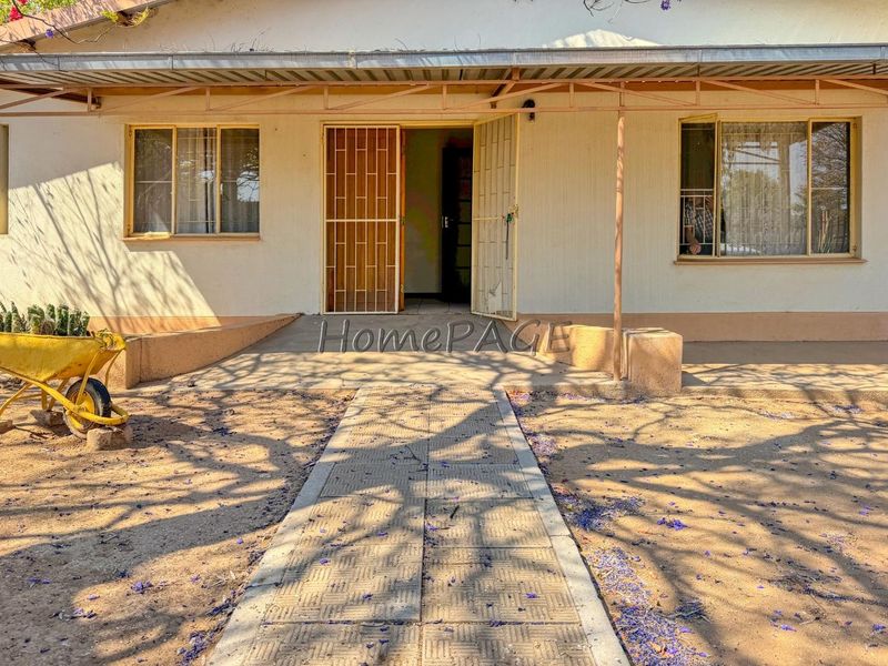 Front exterior view of the house featuring a covered patio area, security gate, and a paved walkway leading to the entrance.