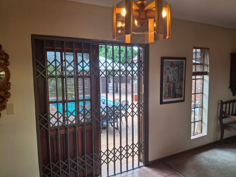 Living area featuring a sliding door with a security gate, providing direct access to the outdoor patio and pool area.