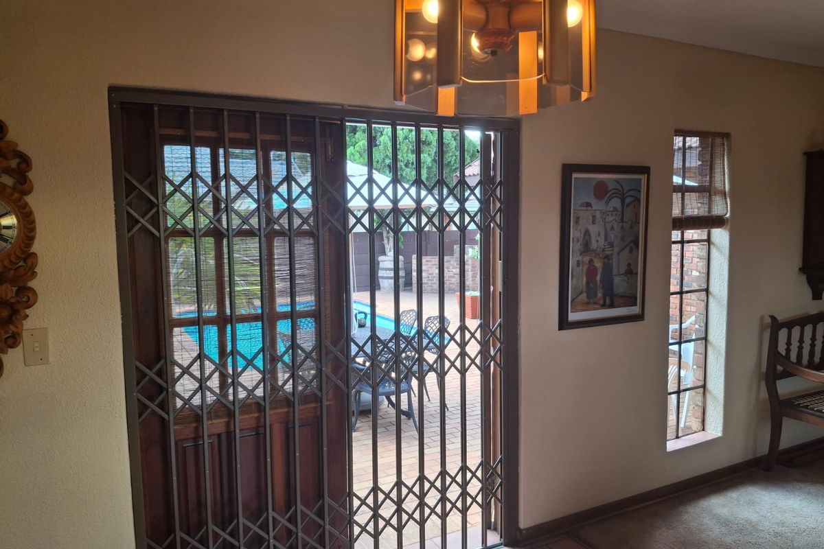 Living area featuring a sliding door with a security gate, providing direct access to the outdoor patio and pool area.