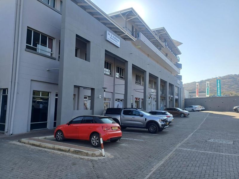 Exterior view of a multi-story commercial office building featuring a paved parking area and modern facade design.