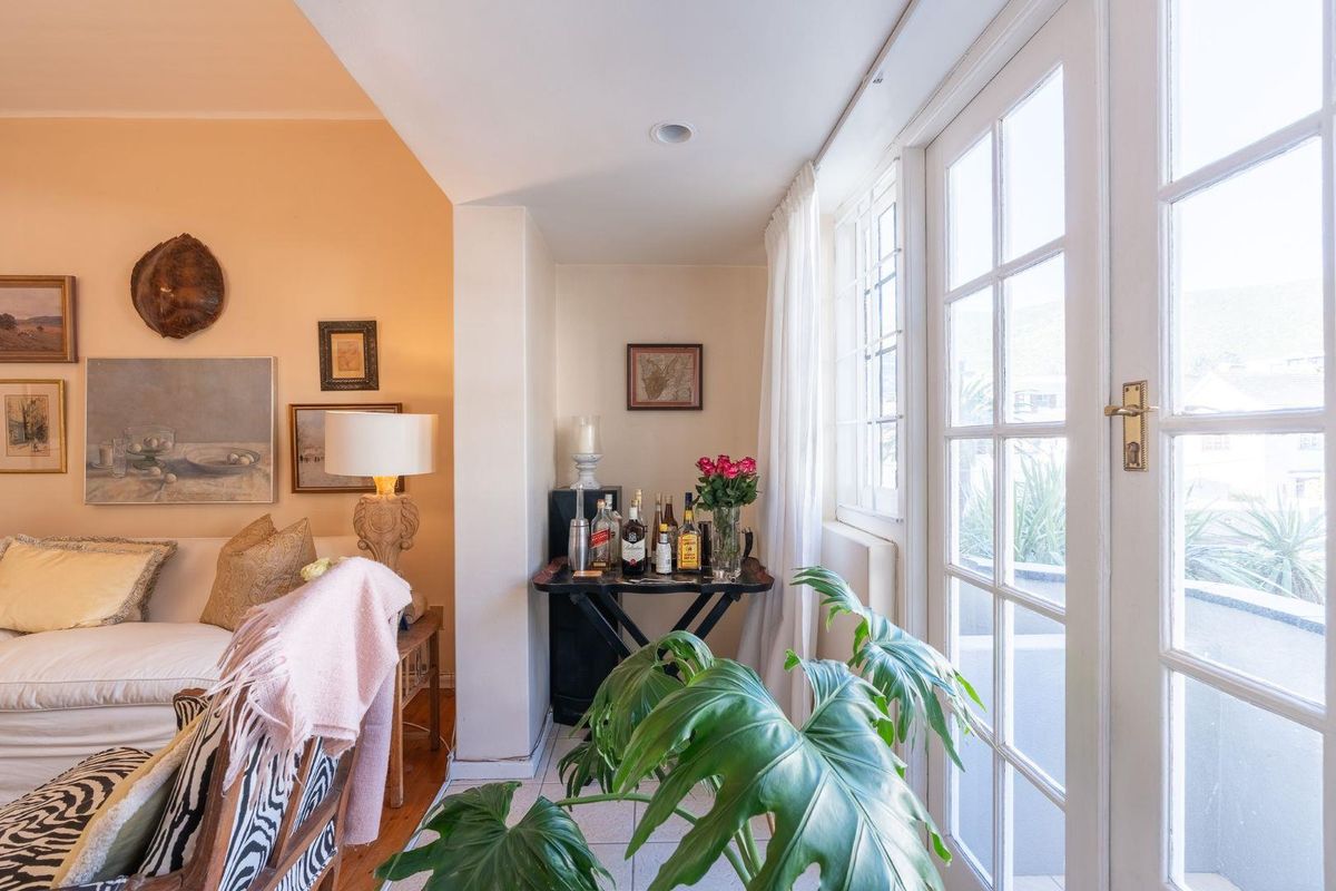 A cozy living room featuring hardwood and tiled flooring, recessed lighting, and classic French doors that provide access to an outdoor area.
