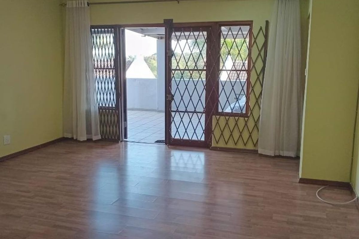 Spacious living area featuring laminate flooring, recessed downlights, and sliding glass doors leading to an outdoor patio area.