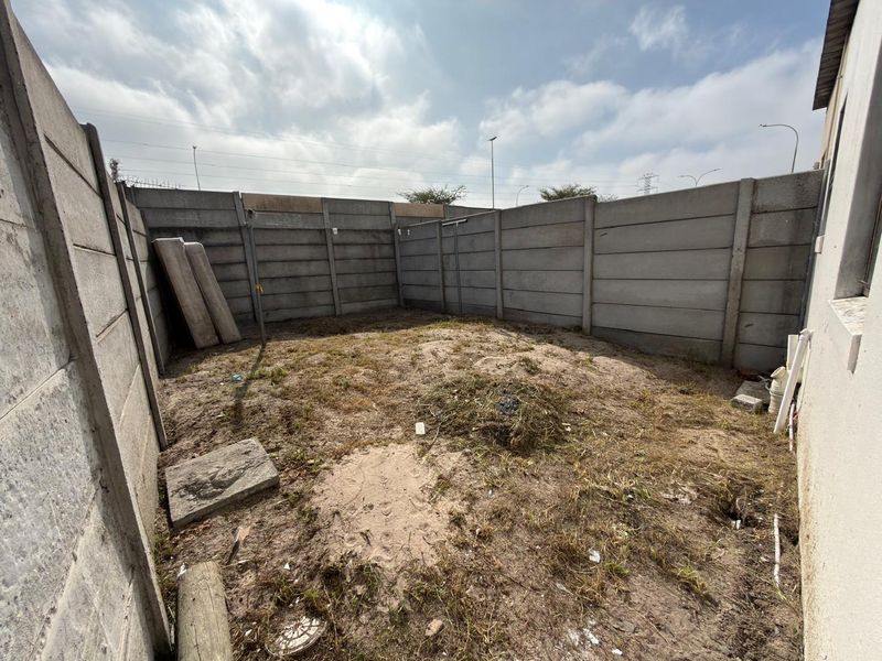 A private rear courtyard area enclosed by precast concrete boundary walls, offering a blank canvas for landscaping or outdoor development.