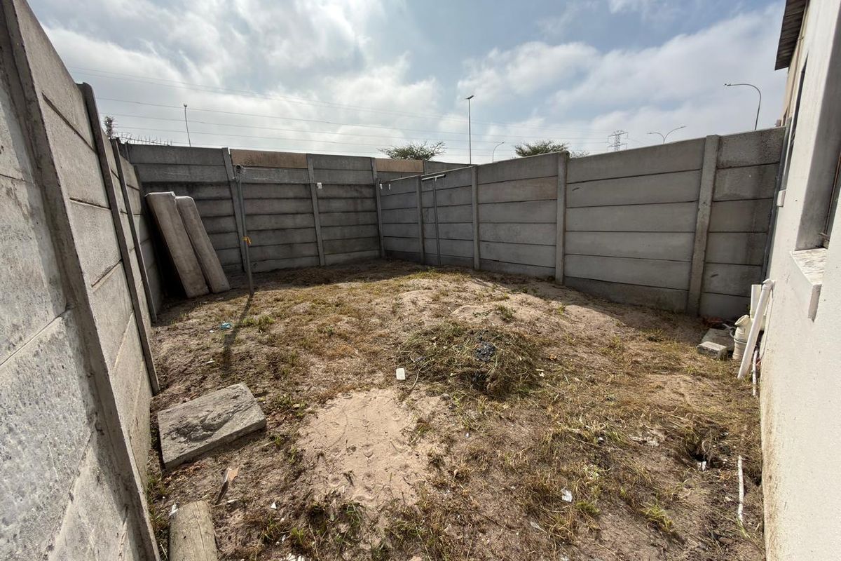 A private rear courtyard area enclosed by precast concrete boundary walls, offering a blank canvas for landscaping or outdoor development.