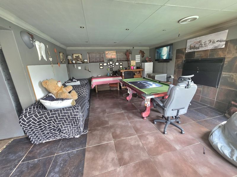 Spacious living area featuring tiled flooring, recessed ceiling lights, and a built-in fireplace with a stone tile surround.