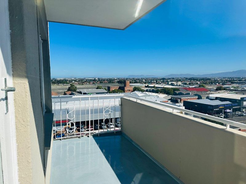 A clean, open-air balcony featuring a metal balustrade and painted concrete flooring, offering expansive elevated views of the surrounding urban landscape.