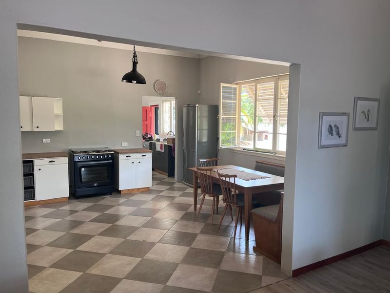 Open-plan kitchen and dining area featuring tiled flooring, built-in cabinetry, a gas stove, and direct access to a secondary scullery space.