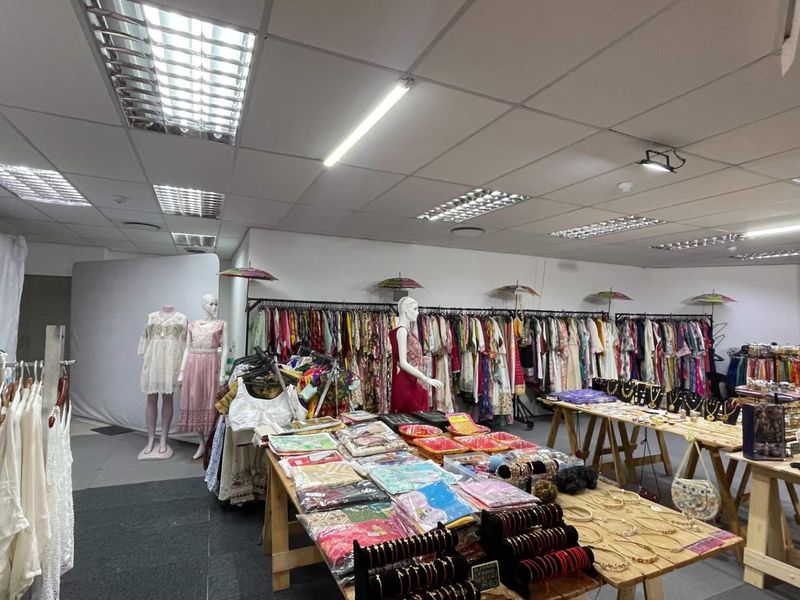 A retail space featuring a suspended ceiling with integrated fluorescent lighting and air conditioning vents, currently utilized as a clothing and accessory boutique.