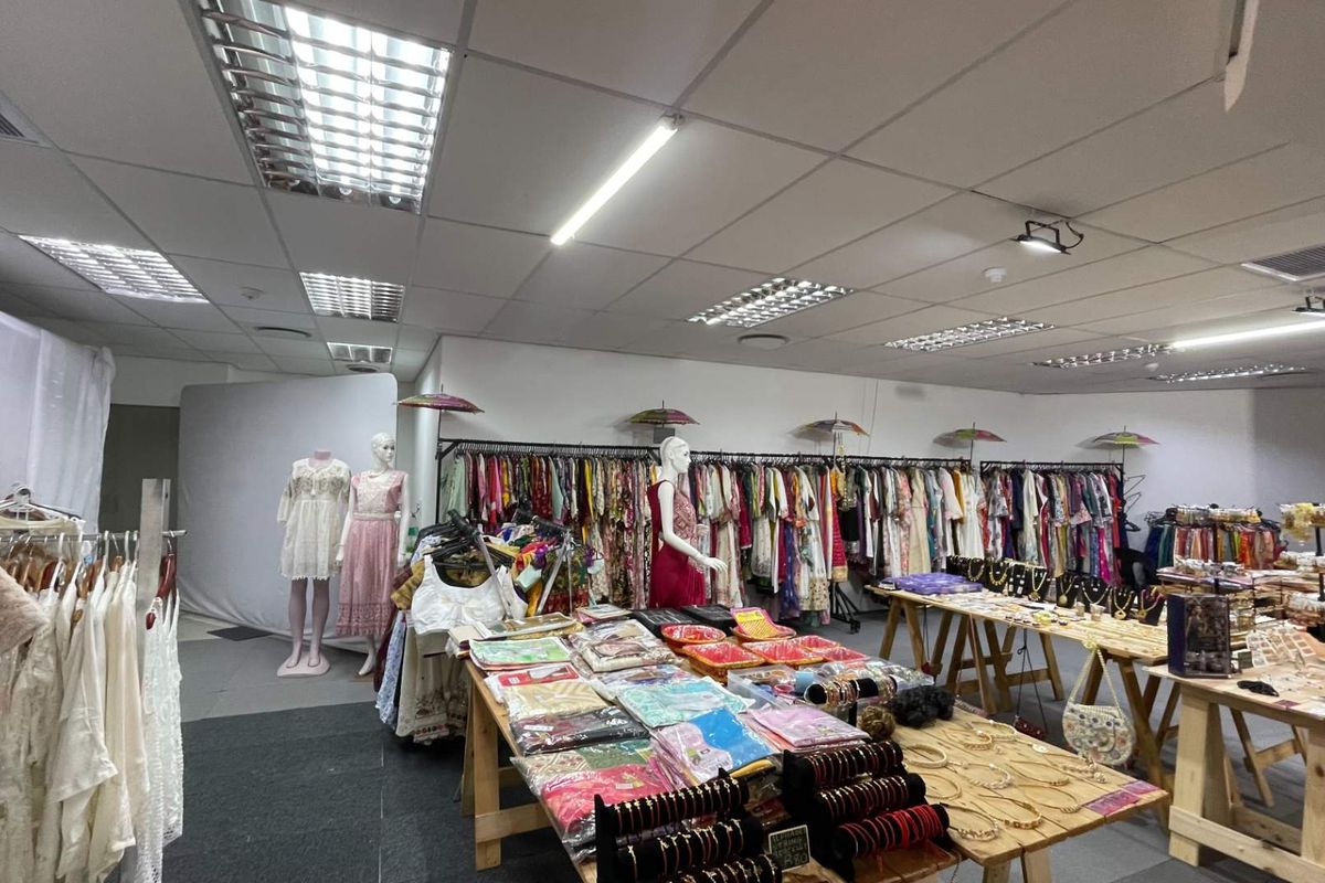 A retail space featuring a suspended ceiling with integrated fluorescent lighting and air conditioning vents, currently utilized as a clothing and accessory boutique.