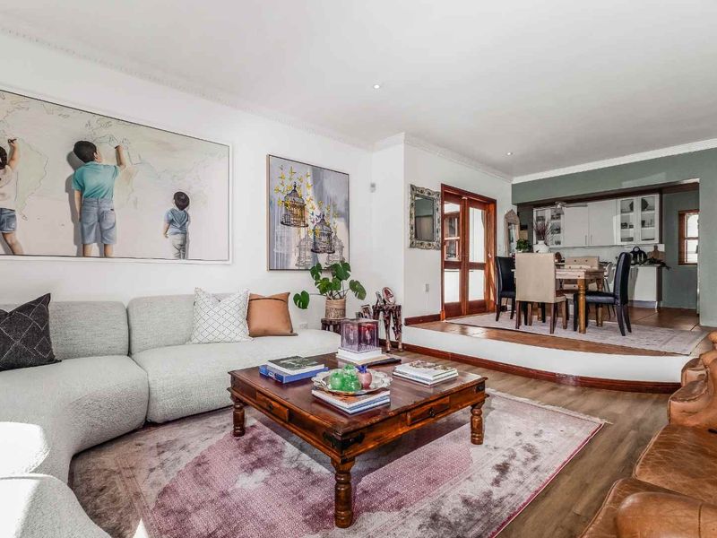 Spacious open-plan living and dining area featuring timber flooring, a raised dining platform, and seamless flow into the adjacent kitchen space.
