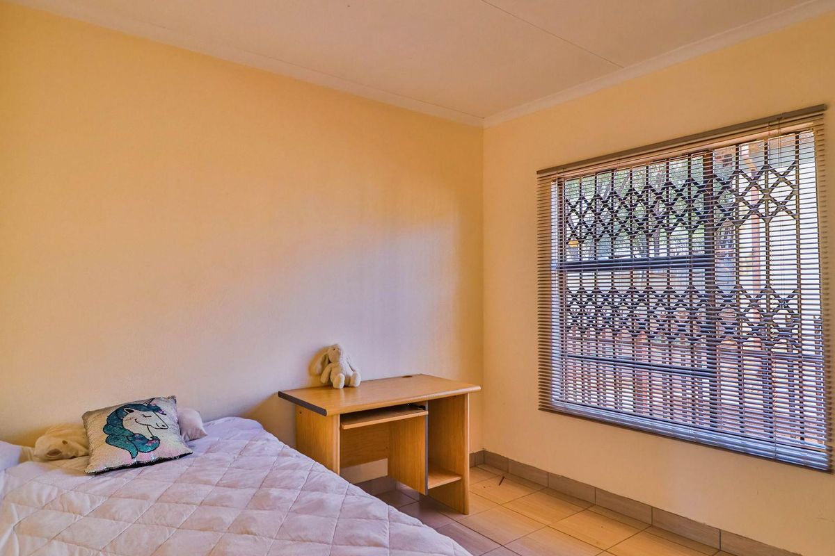 A bedroom featuring tiled flooring and a window fitted with security bars and blinds.