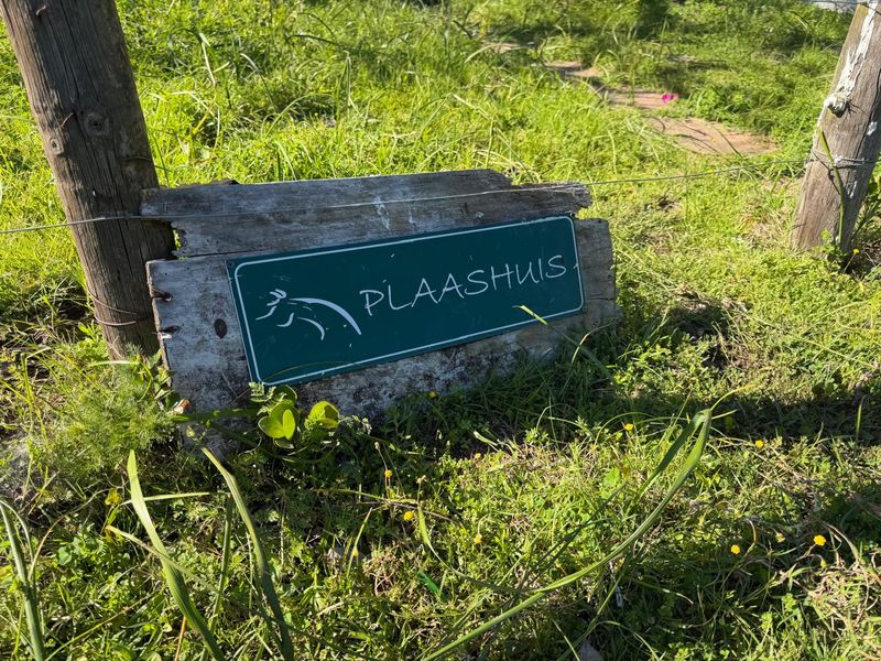 A rustic farm entrance sign mounted on a wooden post and wire fence, marking the property boundary.