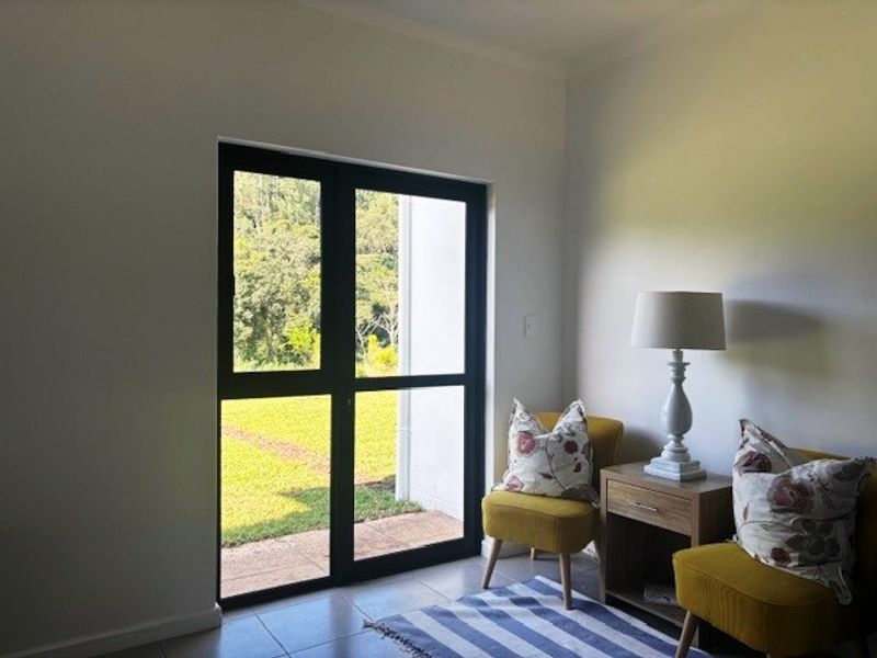 A bright living area featuring modern black aluminium framed glass doors that provide direct access to the outdoor garden space.
