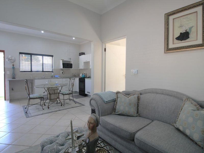 Open-plan living area featuring a functional kitchen with built-in cabinetry, tiled flooring, and recessed lighting, seamlessly connected to the lounge space.