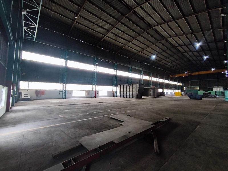 Expansive industrial warehouse space featuring high ceilings, concrete flooring, and steel portal frame construction, suitable for manufacturing or large-scale storage operations.