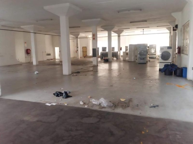 Large open-plan industrial utility space featuring concrete flooring, structural columns, and overhead fluorescent lighting, suitable for various commercial or storage applications.