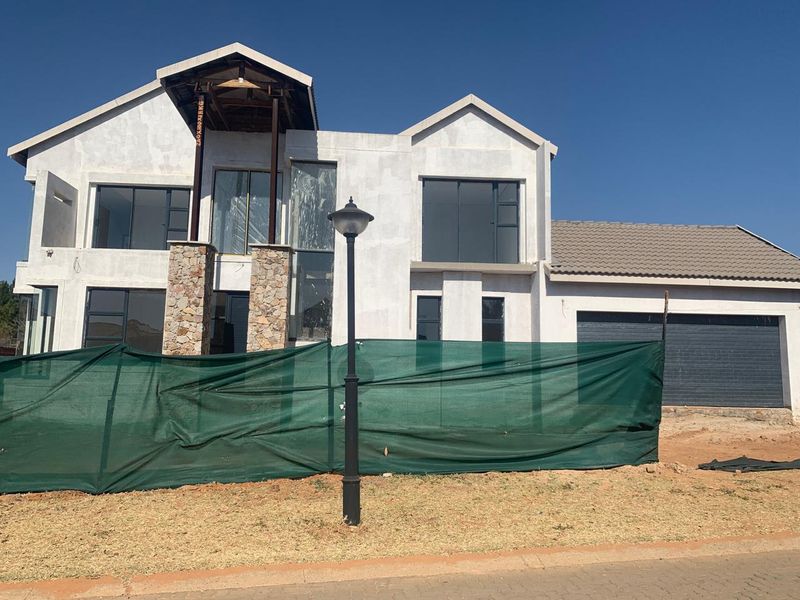 Front elevation of a double-storey residential property under construction, featuring stone cladding accents, aluminium windows, and a double garage.