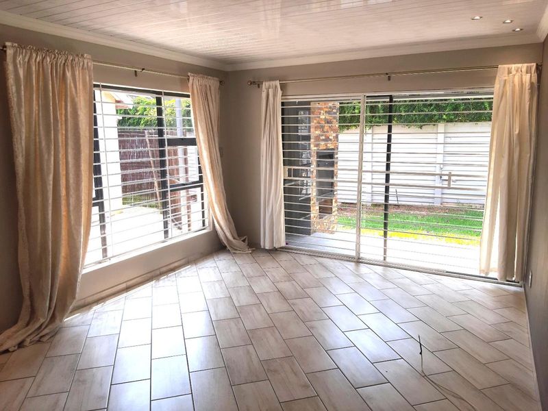 Bright and spacious living area featuring modern tiled flooring, recessed ceiling lights, and large sliding glass doors providing access to the rear garden.