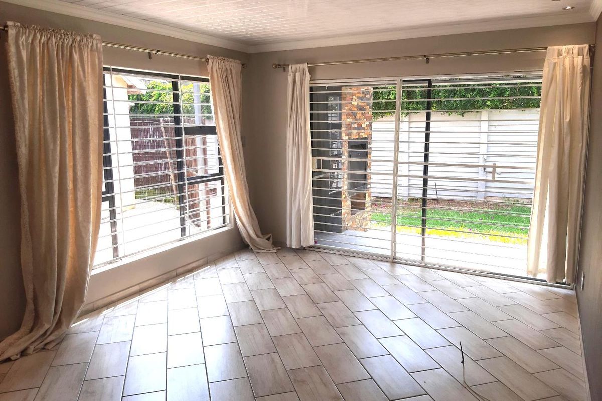 Bright and spacious living area featuring modern tiled flooring, recessed ceiling lights, and large sliding glass doors providing access to the rear garden.
