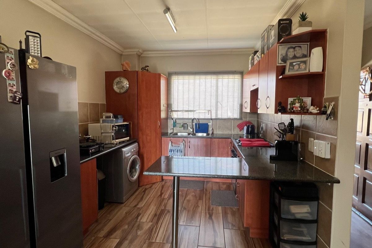 A functional kitchen featuring wood-look floor tiles, granite countertops, ample laminate cabinetry, and a double bowl sink with a tiled backsplash.