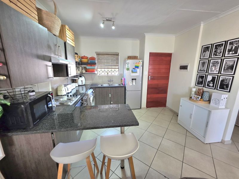 A functional kitchen featuring dark wood cabinetry, granite countertops, a breakfast bar, and tiled flooring, providing a practical and well-maintained cooking space.