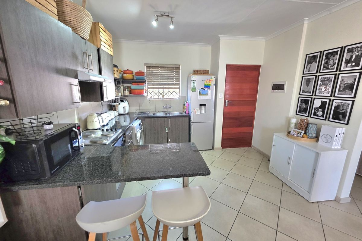 A functional kitchen featuring dark wood cabinetry, granite countertops, a breakfast bar, and tiled flooring, providing a practical and well-maintained cooking space.