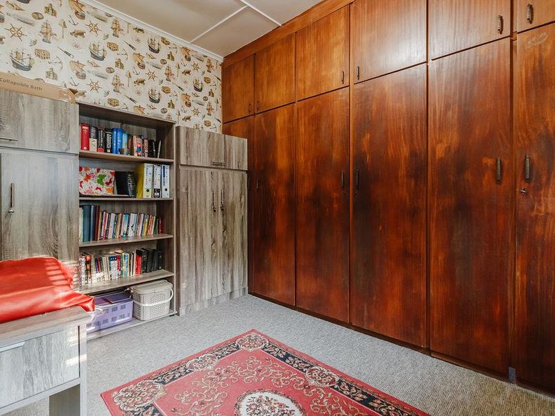 Bedroom featuring extensive floor-to-ceiling built-in wooden cupboards and integrated shelving units.