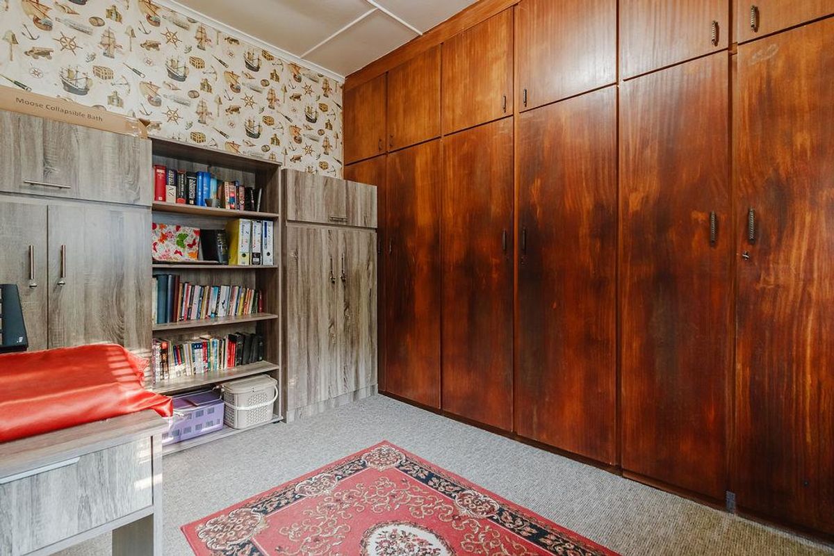 Bedroom featuring extensive floor-to-ceiling built-in wooden cupboards and integrated shelving units.