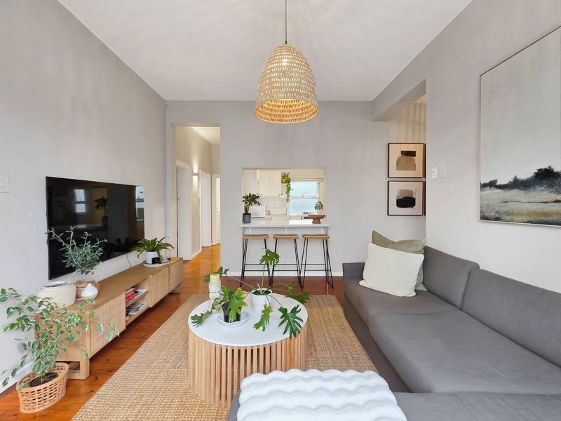 A well-maintained living room featuring warm hardwood flooring and a convenient pass-through window connecting to the kitchen area.