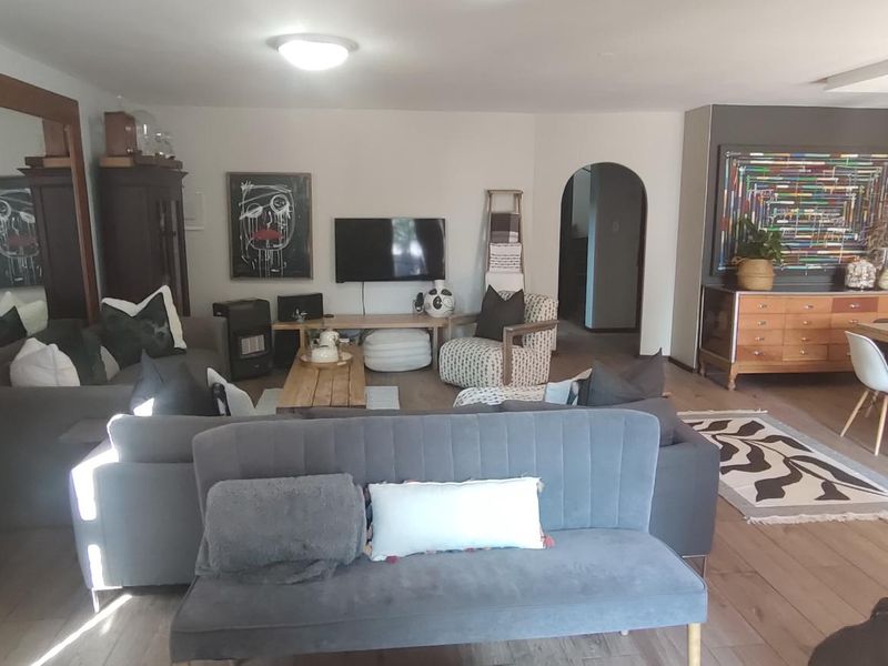 Spacious open-plan living and dining area featuring laminate flooring, an arched entryway, and modern pendant lighting, creating a versatile and inviting living space.