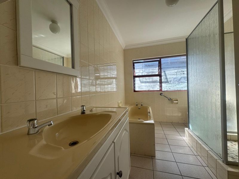 A functional bathroom featuring a built-in vanity, bathtub, and separate shower enclosure with tiled finishes throughout.