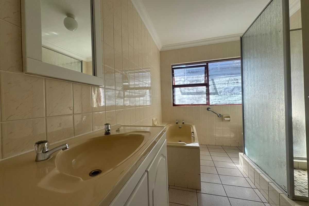 A functional bathroom featuring a built-in vanity, bathtub, and separate shower enclosure with tiled finishes throughout.