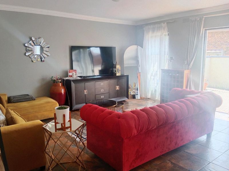 A living room featuring tiled flooring, cove cornicing, and a sliding glass door providing access to the outdoor area.