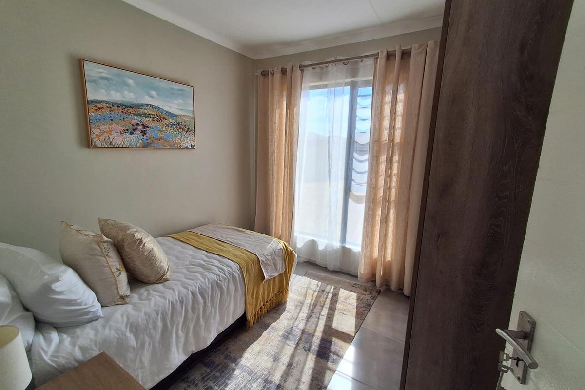 A well-lit bedroom featuring neutral wall tones, tiled flooring, and a built-in cupboard, offering a comfortable and functional living space.