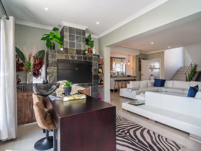 Open-plan living area featuring a built-in fireplace with stone tiling, flowing into a kitchen and dining space with modern finishes and recessed lighting.
