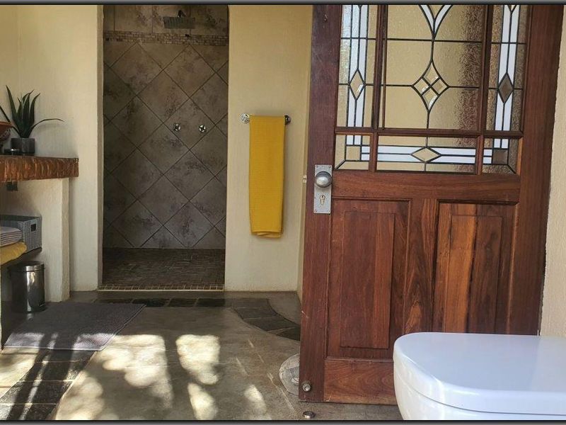 A bathroom featuring a walk-in shower with tiled walls, a built-in vanity with a vessel sink, and a decorative leaded glass timber door.