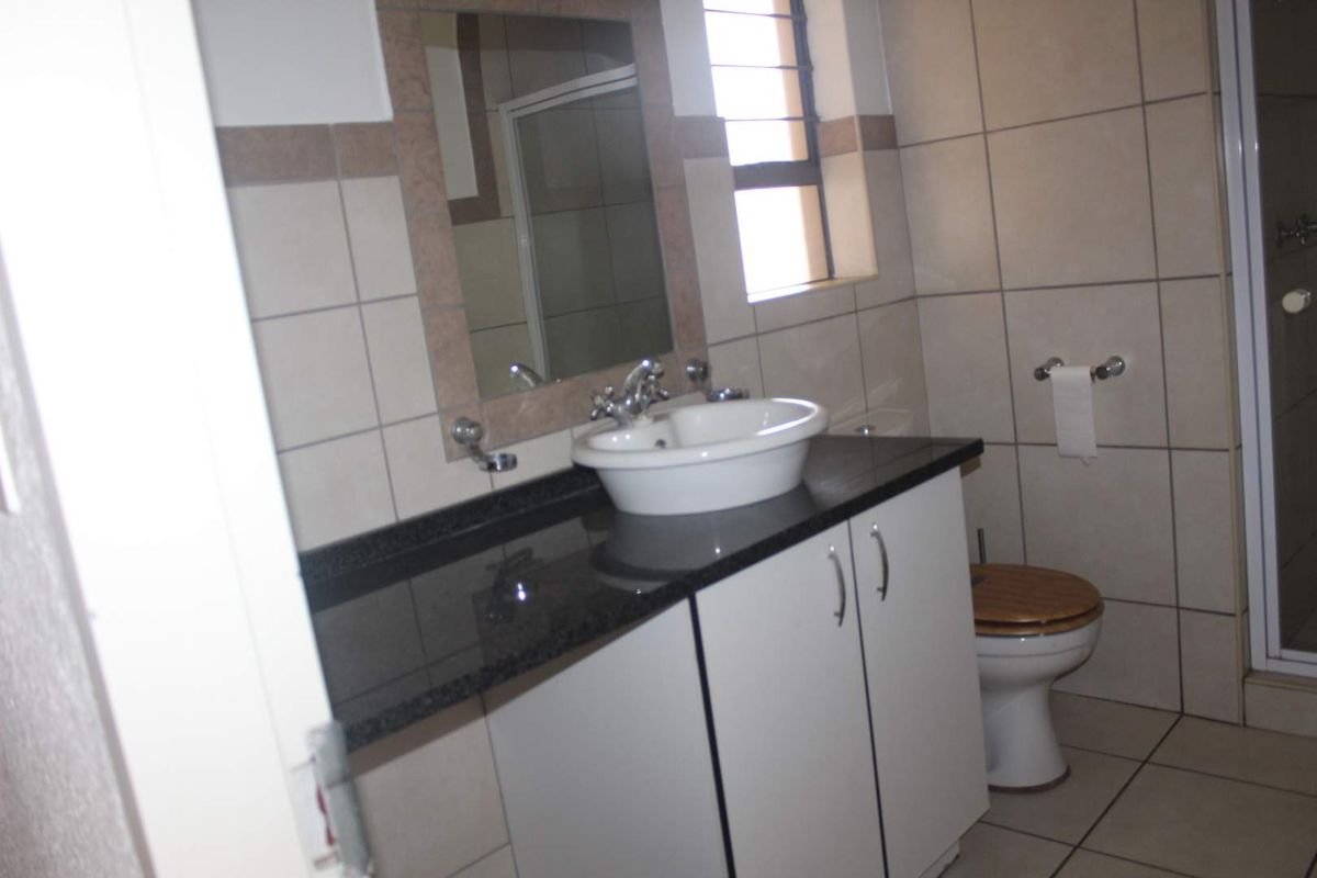 A functional bathroom featuring a vanity with a granite countertop, vessel sink, tiled walls, and a separate shower enclosure.