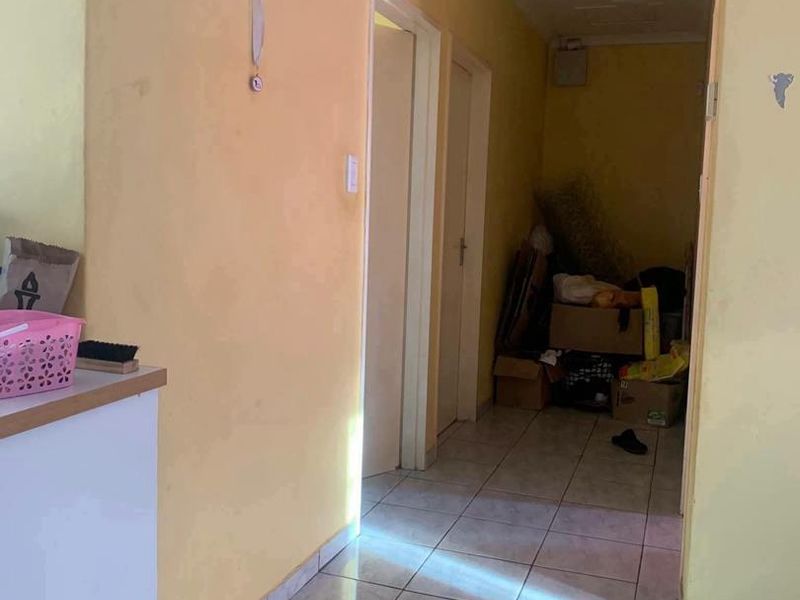 A functional hallway featuring tiled flooring and yellow painted walls, providing access to adjacent rooms.