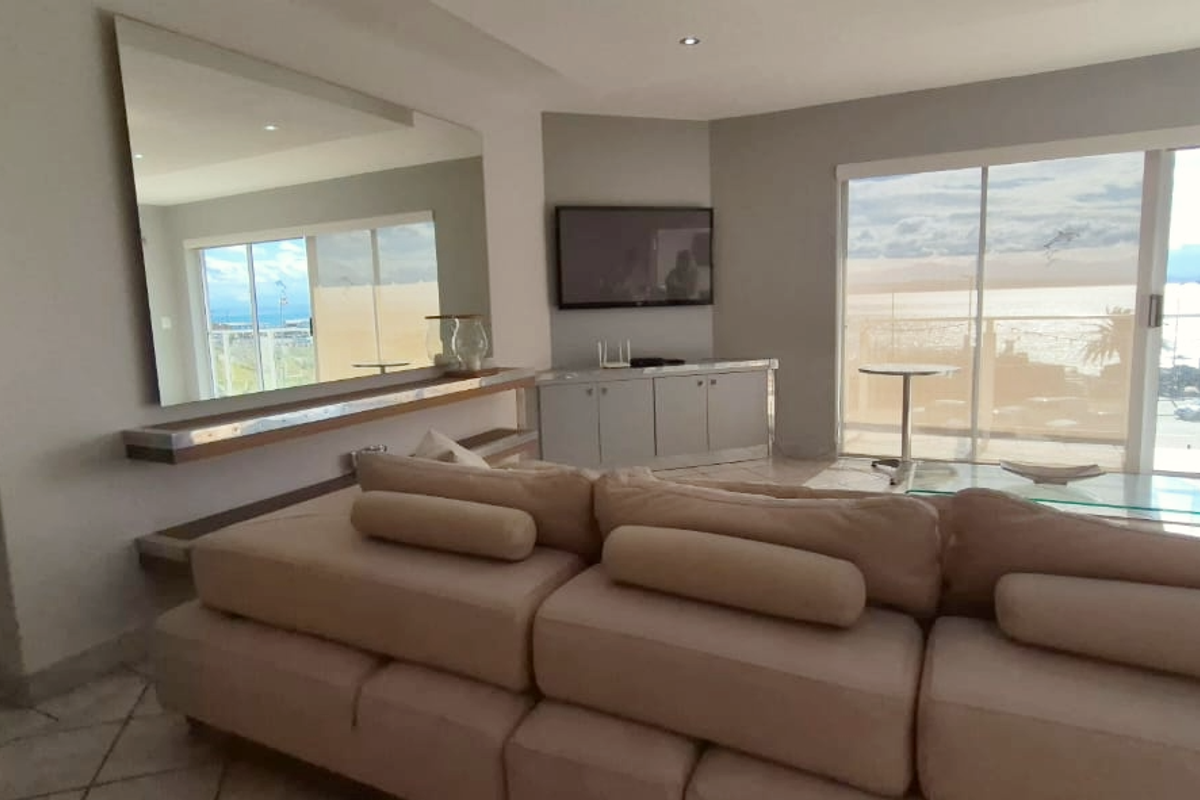 Spacious living area featuring large sliding glass doors with ocean views, built-in cabinetry, and a large wall-mounted mirror.