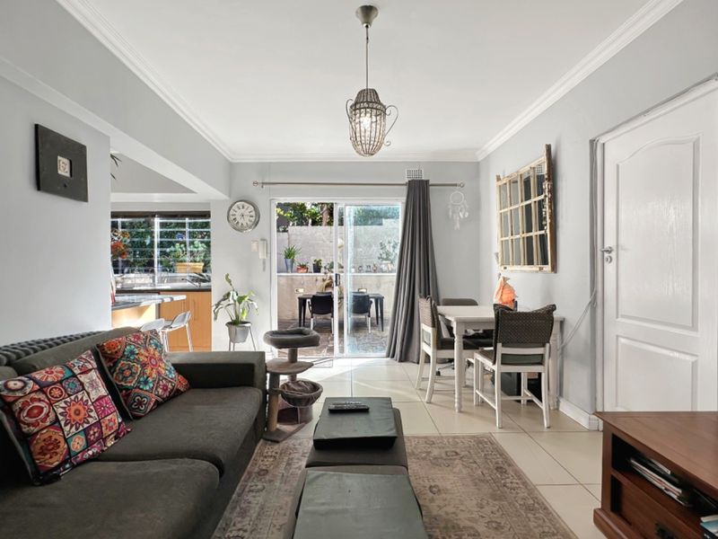 An open-plan living and dining area featuring tiled floors, crown molding, and a sliding glass door leading to an outdoor patio space.