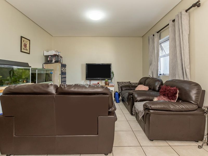 A functional living room featuring neutral wall tones and tiled flooring, providing a comfortable and practical space for relaxation.