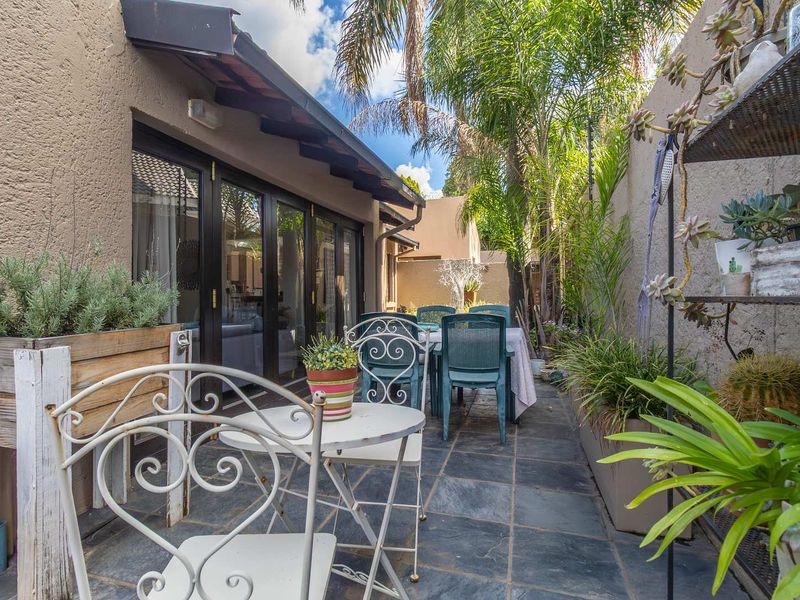A private outdoor patio area featuring slate tile flooring, accessible through large glass sliding doors, surrounded by established garden greenery.