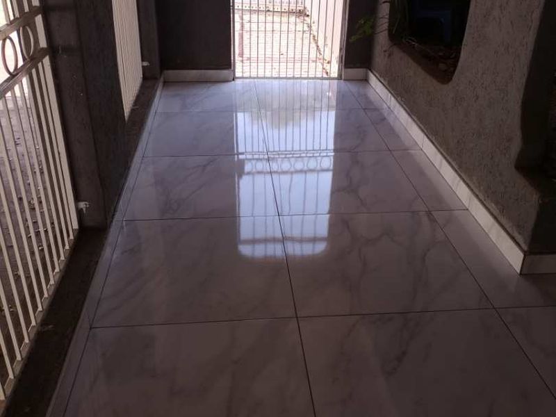 A covered patio area featuring polished marble-look floor tiles and secure metal gate access.