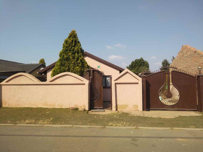Front view of the property featuring a gated entrance, perimeter wall, and driveway access from the street.