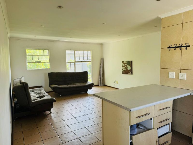 Open plan living area featuring tiled flooring, recessed lighting, and a kitchen island with built-in cabinetry and laminate countertops.