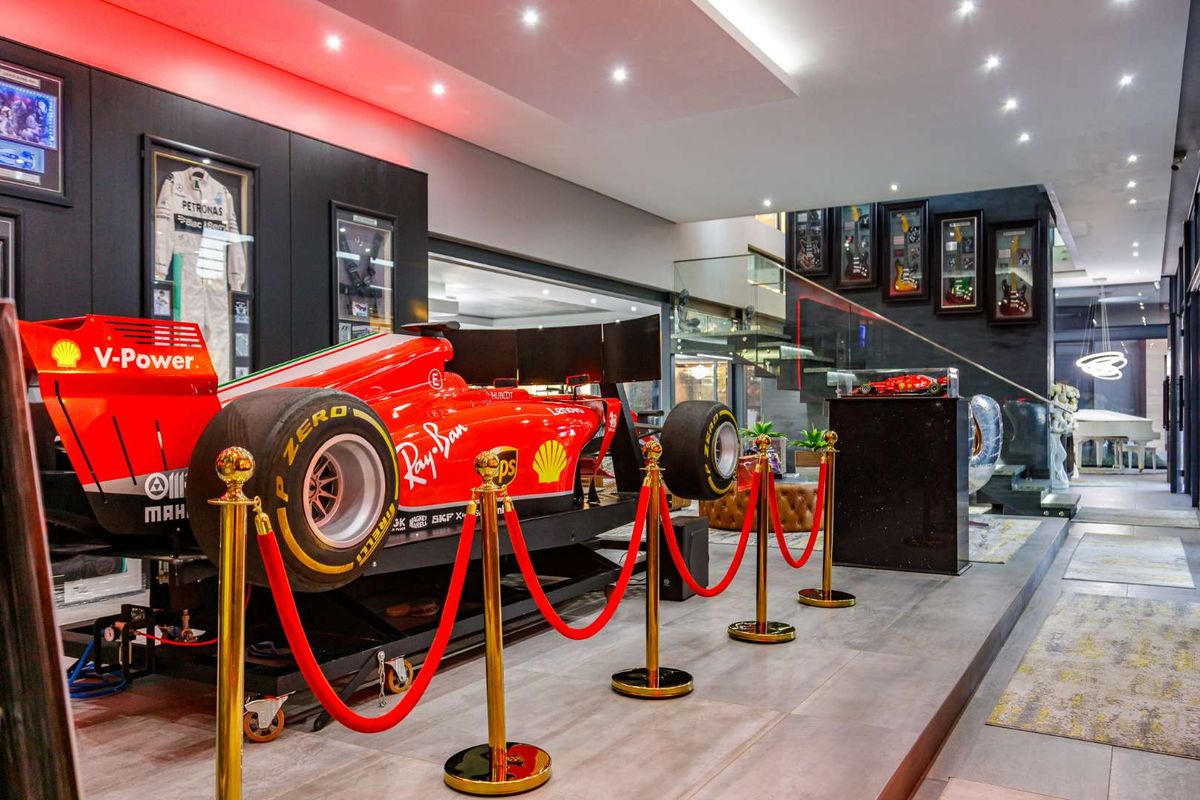 A high-end, modern entertainment space featuring recessed ceiling lighting, tiled flooring, and a glass-railed staircase, designed as a luxury display area.