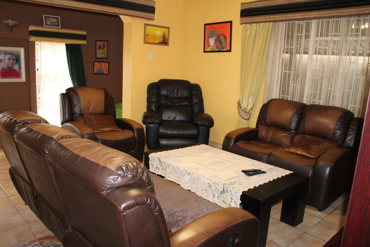 A living room area featuring tiled flooring and large windows with security bars, providing a functional and comfortable space.