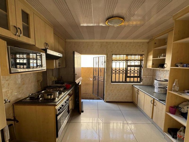 A functional kitchen featuring built-in cabinetry, a built-in oven with hob, and direct access to an outdoor area through a security gate.