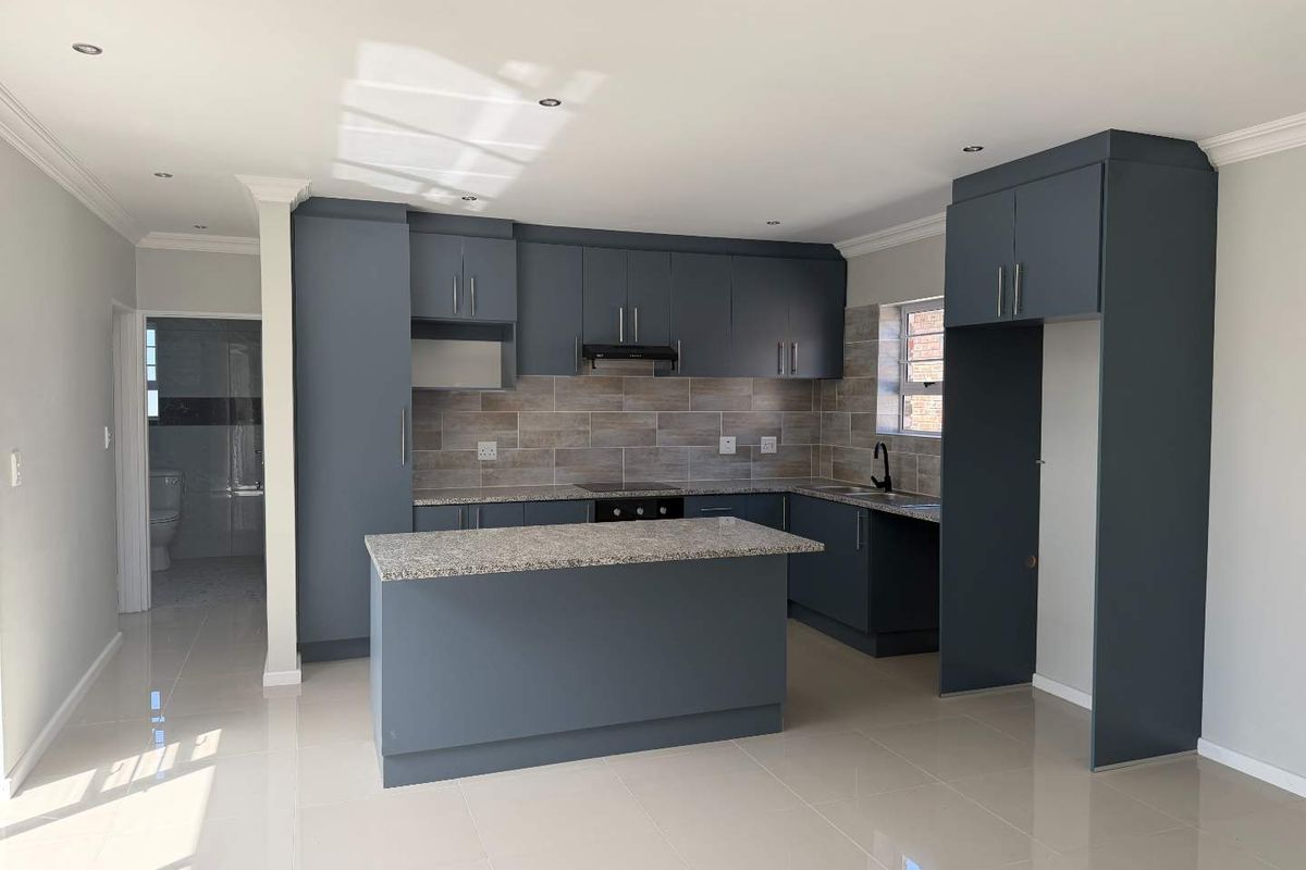 Modern kitchen featuring dark blue cabinetry, granite countertops, a central island, and tiled backsplash, finished with sleek porcelain flooring and recessed lighting.